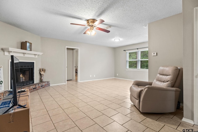 18396 Tall Pines Dr, Tyler, TX 75703 - living area with a ceiling fan, a textured ceiling, a fireplace, light tile patterned flooring, and baseboards
