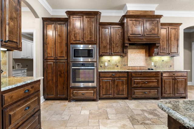 kitchen with stone tile flooring, light stone countertops, arched walkways, and stainless steel appliances