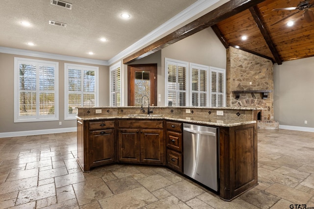 kitchen featuring baseboards, lofted ceiling with beams, stainless steel dishwasher, stone tile flooring, and a sink