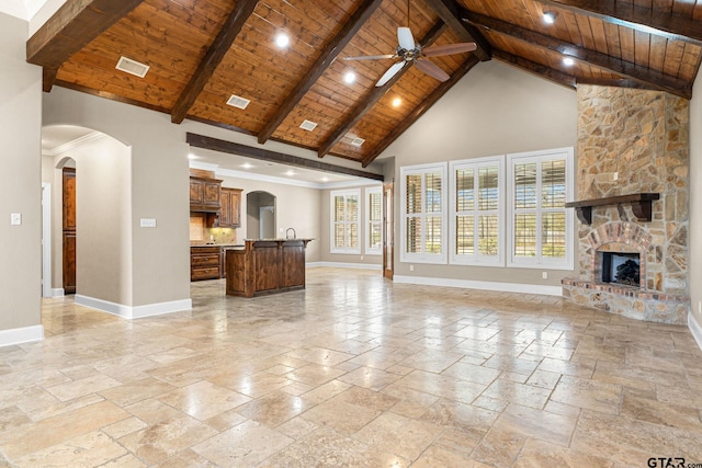 unfurnished living room with baseboards, wood ceiling, a stone fireplace, stone tile flooring, and high vaulted ceiling