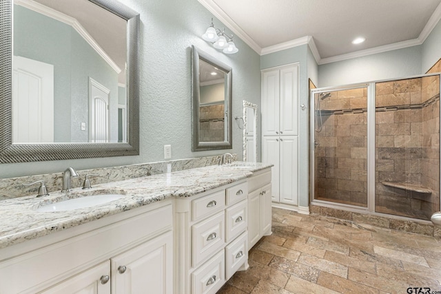 full bath with a sink, a shower stall, and crown molding