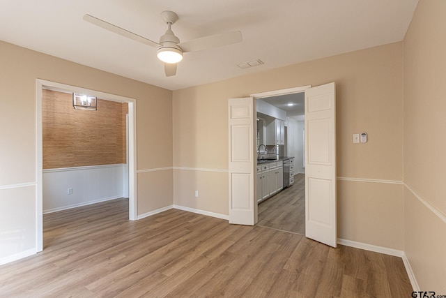 unfurnished room featuring light hardwood / wood-style floors, ceiling fan, and sink