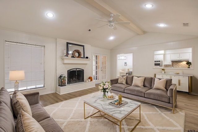 living room with a fireplace, lofted ceiling with beams, light hardwood / wood-style flooring, and ceiling fan