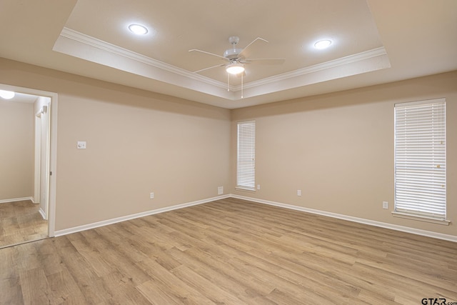 unfurnished room with light hardwood / wood-style flooring, a raised ceiling, and crown molding