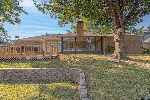 rear view of property with a lawn, a sunroom, and a deck