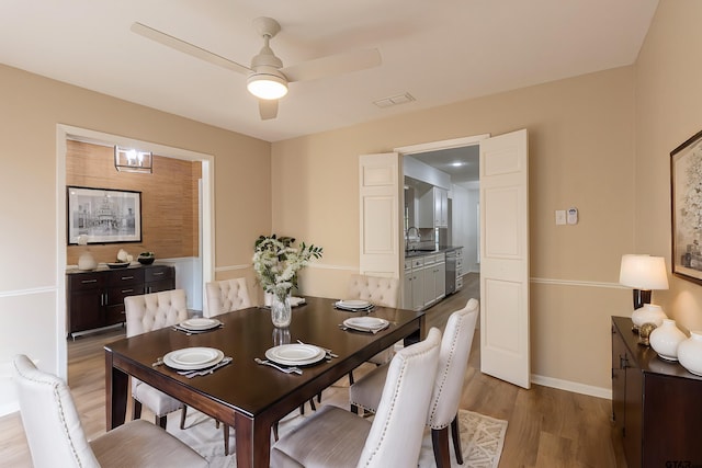 dining room with light wood-type flooring, ceiling fan, and sink