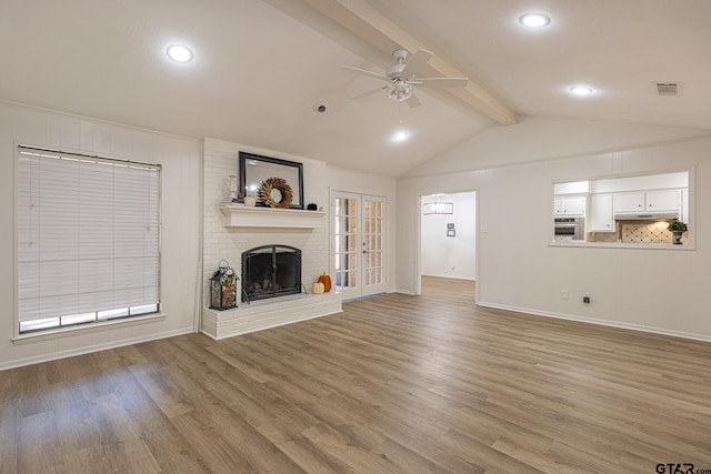 unfurnished living room featuring a fireplace, wood-type flooring, vaulted ceiling with beams, and ceiling fan