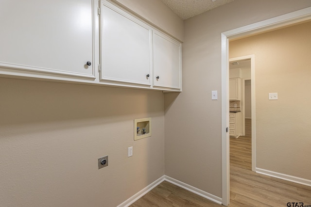 washroom featuring cabinets, washer hookup, a textured ceiling, electric dryer hookup, and light hardwood / wood-style floors