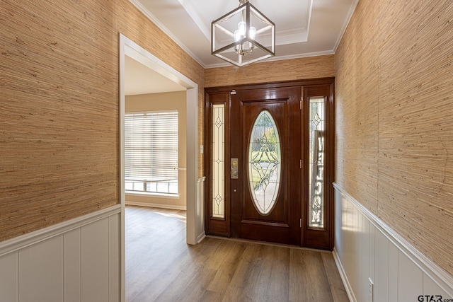 foyer with hardwood / wood-style flooring, a healthy amount of sunlight, crown molding, and an inviting chandelier