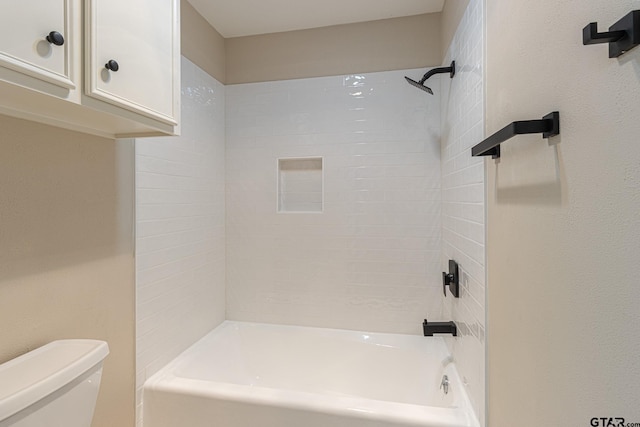 bathroom with tiled shower / bath combo and toilet