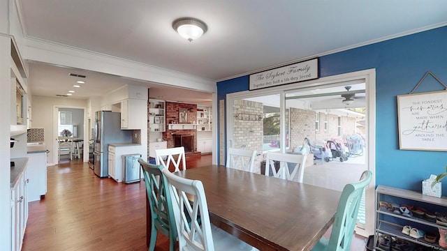 dining room featuring dark hardwood / wood-style flooring, a brick fireplace, and ornamental molding