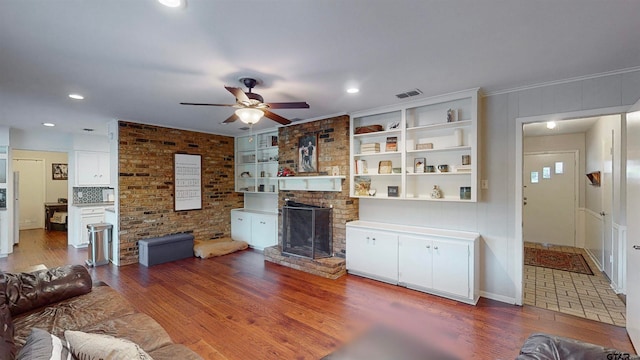 living room featuring hardwood / wood-style floors, a brick fireplace, and ceiling fan