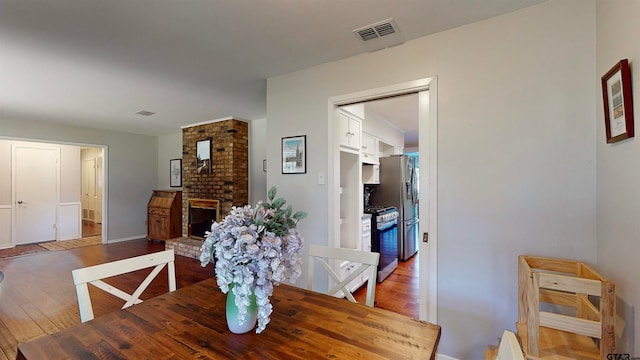 dining area featuring a brick fireplace and hardwood / wood-style flooring