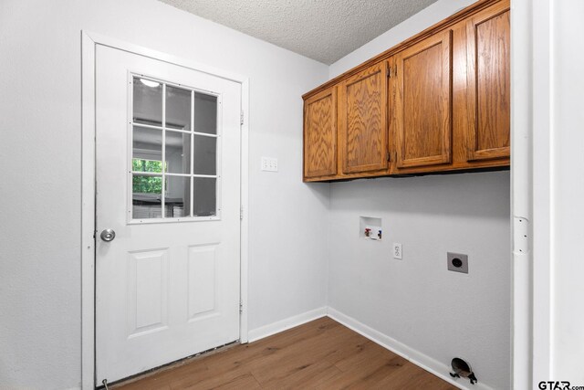 laundry area with hookup for a washing machine, wood finished floors, electric dryer hookup, cabinet space, and baseboards