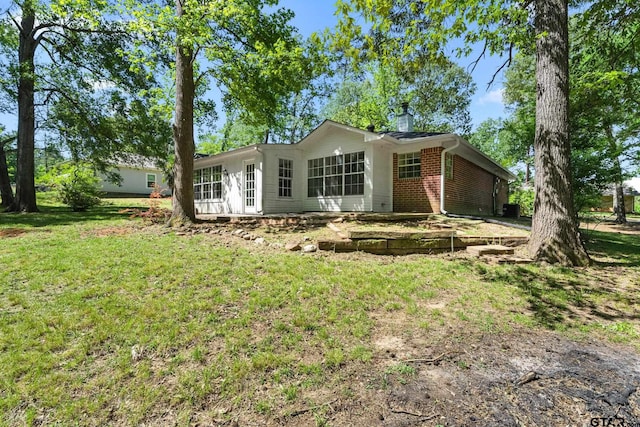 rear view of property featuring a lawn and brick siding