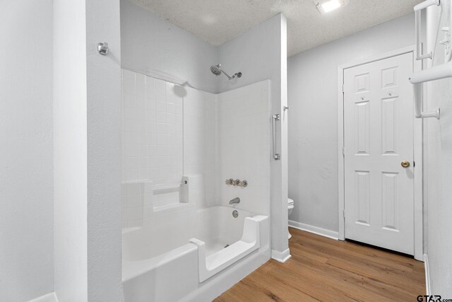 full bathroom with baseboards, wood finished floors,  shower combination, and toilet