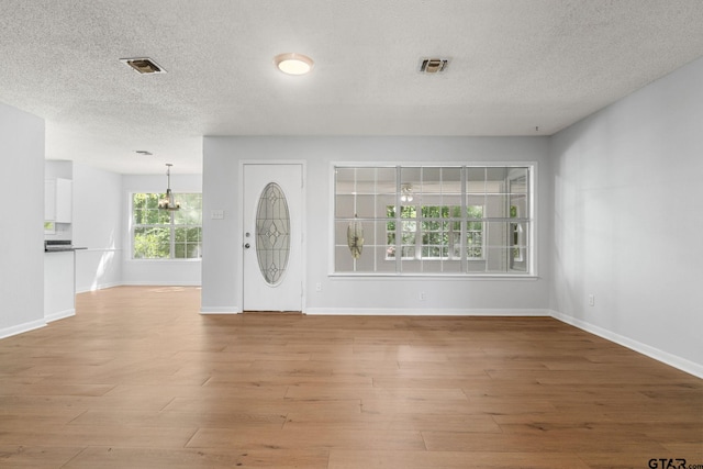 foyer entrance with baseboards, visible vents, and a textured ceiling