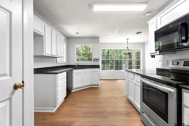kitchen featuring white cabinets, dark countertops, a sink, light wood-type flooring, and black appliances