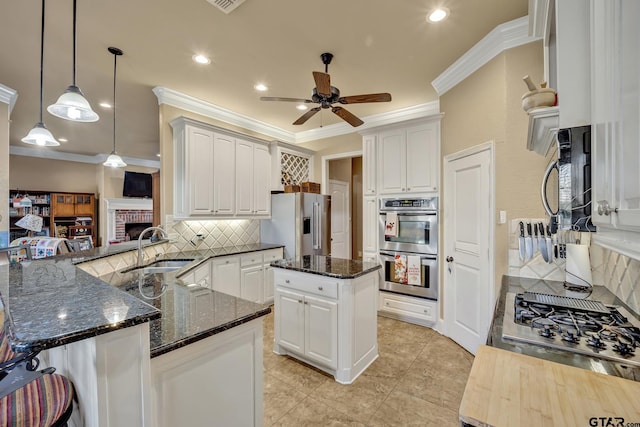 kitchen with white cabinets, kitchen peninsula, sink, ornamental molding, and appliances with stainless steel finishes