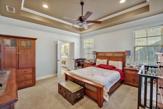 bedroom with ensuite bathroom, multiple windows, a raised ceiling, and ceiling fan