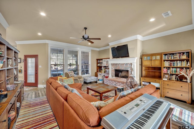 living room with a fireplace, light hardwood / wood-style floors, ceiling fan, and ornamental molding