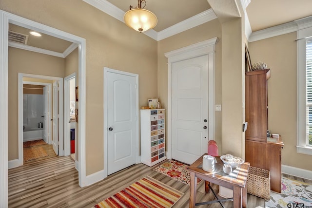 entryway with ornamental molding and light hardwood / wood-style flooring