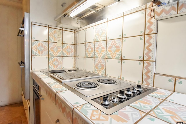 kitchen with tile counters, decorative backsplash, and stovetop