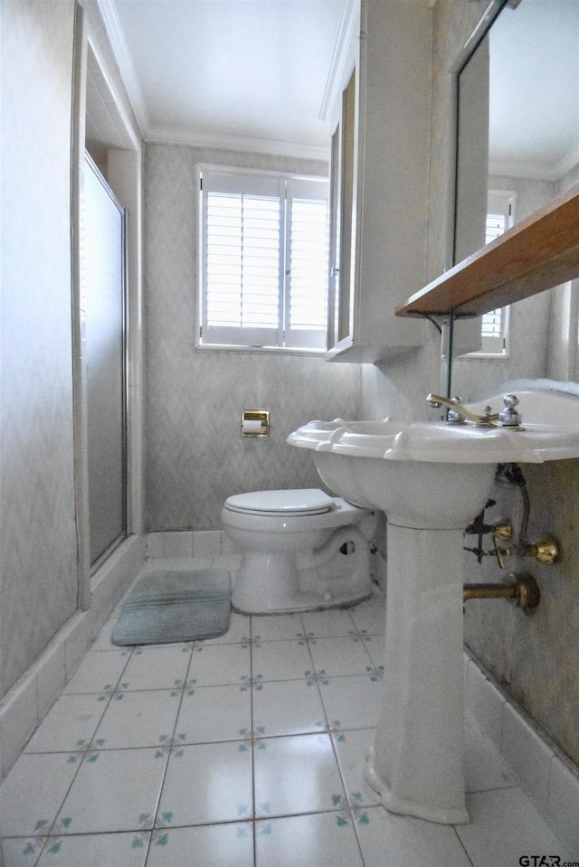 bathroom with toilet, ornamental molding, and a shower with shower door