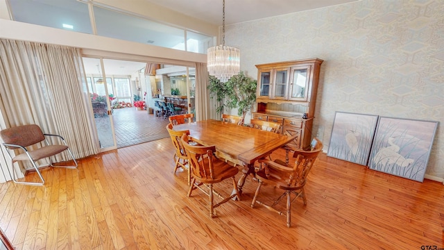 dining space with a notable chandelier, light wood-type flooring, and a high ceiling