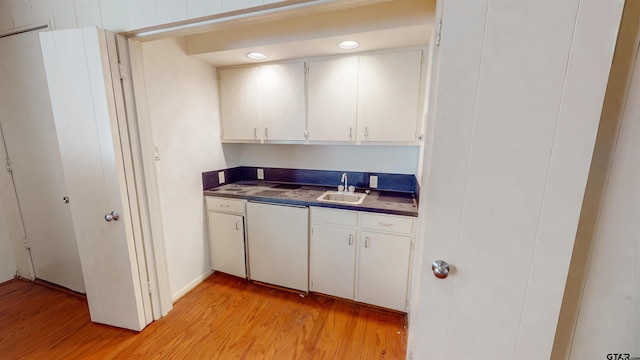 kitchen with sink, light wood-type flooring, dishwasher, and white cabinetry