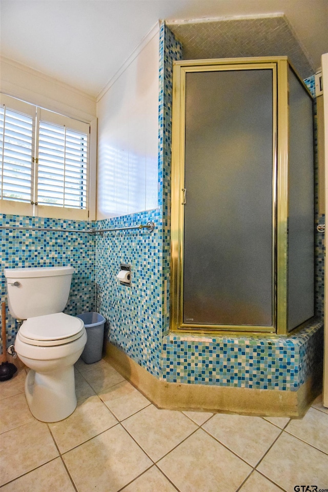 bathroom featuring tile patterned flooring, tile walls, ornamental molding, toilet, and a shower with door