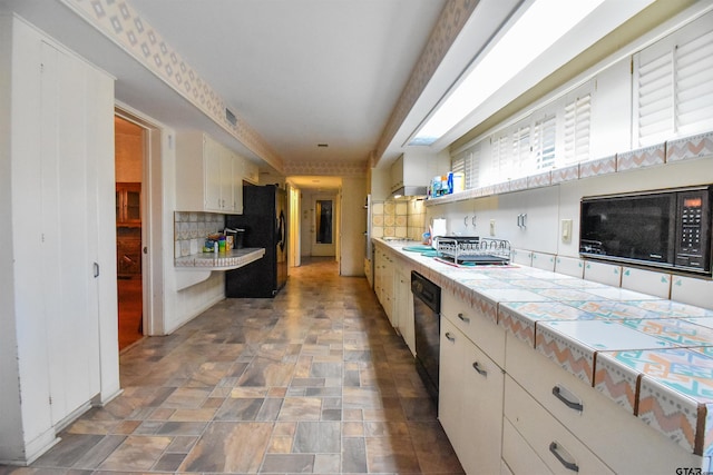 kitchen featuring white cabinets, black appliances, tile counters, and decorative backsplash