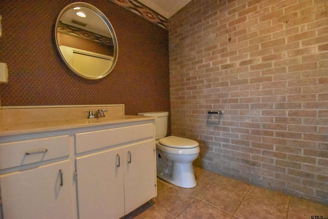 bathroom featuring brick wall, tile patterned flooring, vanity, and toilet