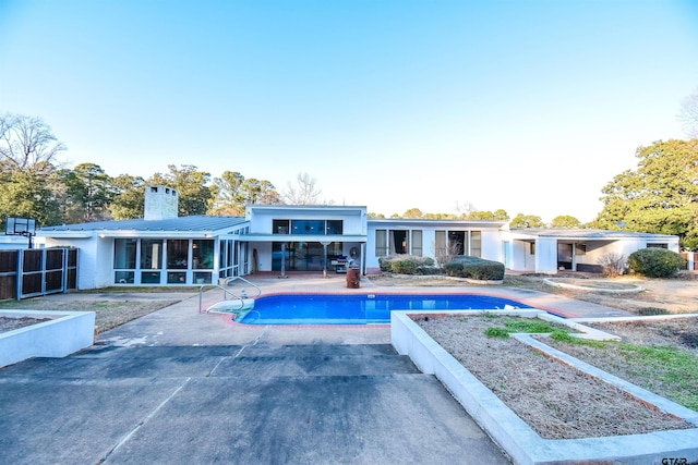 view of pool with a sunroom and a patio