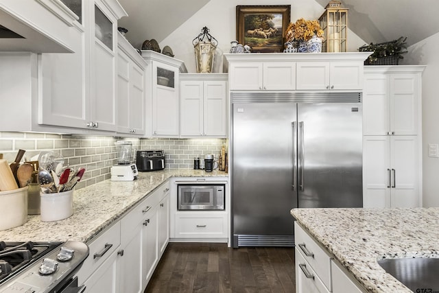 kitchen with backsplash, white cabinets, dark hardwood / wood-style floors, and built in appliances