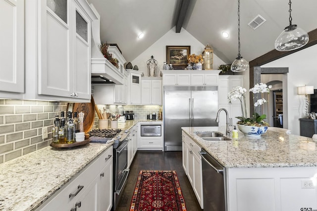 kitchen with white cabinetry, built in appliances, sink, hanging light fixtures, and lofted ceiling with beams