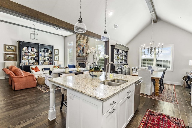 kitchen featuring white cabinetry, a kitchen island with sink, light stone countertops, pendant lighting, and sink