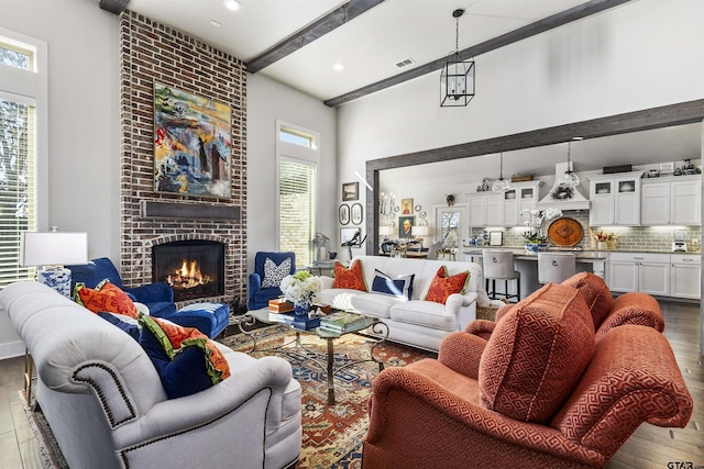 living room with hardwood / wood-style flooring, a high ceiling, beamed ceiling, and a fireplace