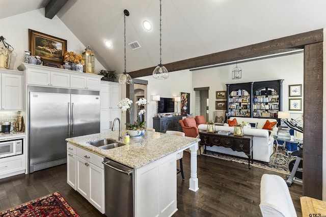 kitchen featuring white cabinetry, sink, a center island with sink, and built in appliances