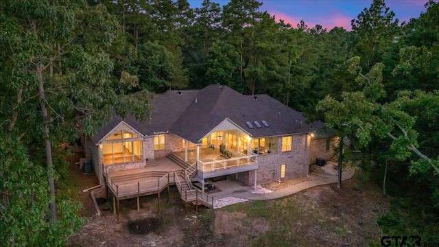 back house at dusk with cooling unit, a deck, and a patio area