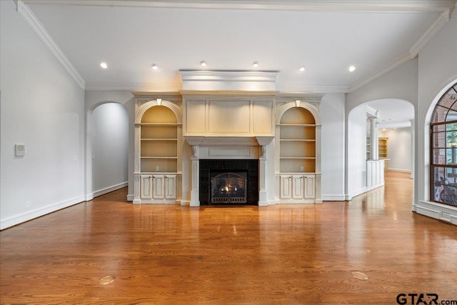 unfurnished living room with ornamental molding, built in features, and wood-type flooring