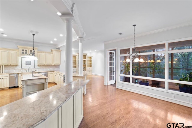 kitchen with cream cabinets, tasteful backsplash, decorative columns, light stone countertops, and light wood-type flooring