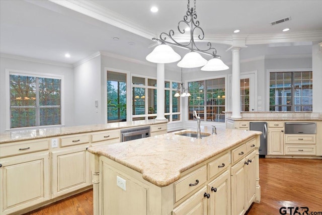 kitchen with a kitchen island with sink, a healthy amount of sunlight, ornate columns, and pendant lighting