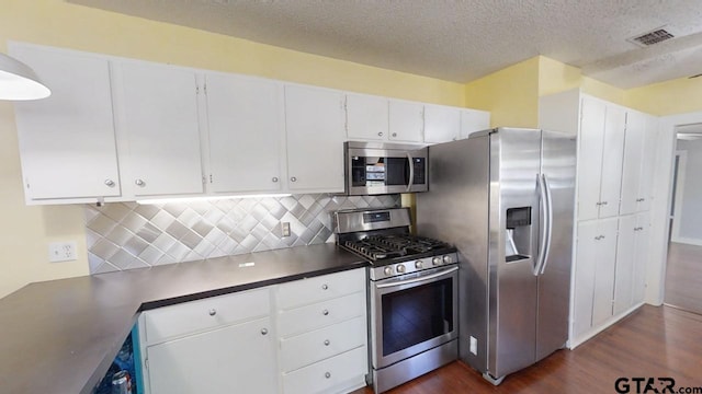 280 Dickard St, Hawkins, TX 75765 - kitchen with visible vents, decorative backsplash, appliances with stainless steel finishes, white cabinetry, and dark wood-style flooring