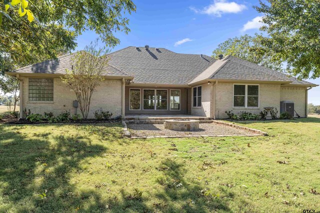1036 High Meadow Dr, Mount Vernon, TX 75457 - rear view of house featuring an outdoor fire pit, brick siding, a lawn, roof with shingles, and a patio area