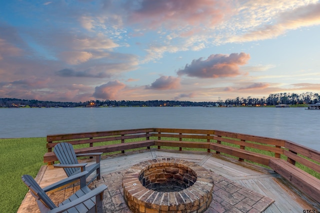 patio terrace at dusk with a fire pit and a water view