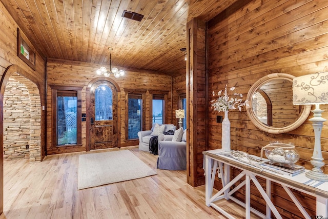 foyer with wood walls, wood ceiling, and light wood-type flooring