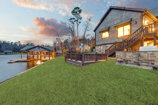 view of yard with a wooden deck, a boat dock, and stairs