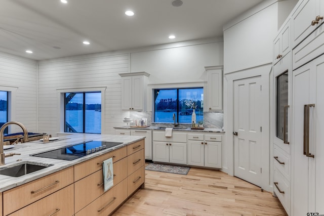 kitchen with a sink, backsplash, recessed lighting, and light wood finished floors