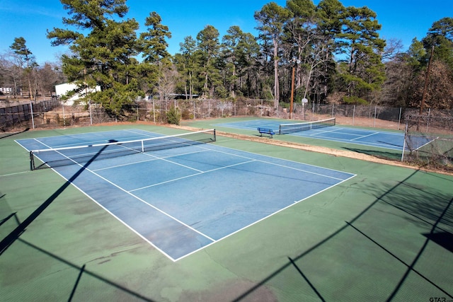 view of tennis court featuring community basketball court and fence